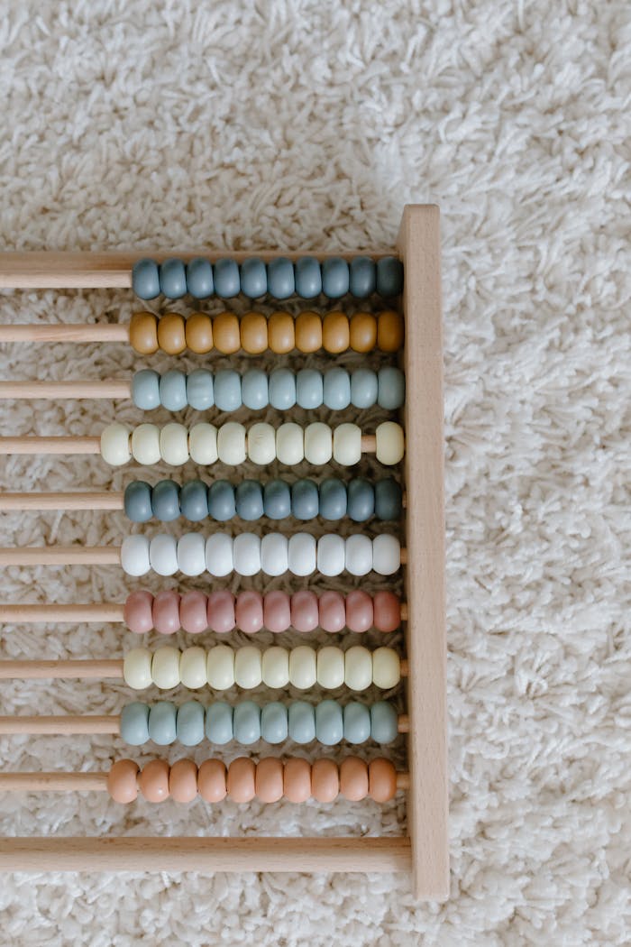 A pastel-colored wooden abacus laid on a soft carpet, perfect for educational decor.